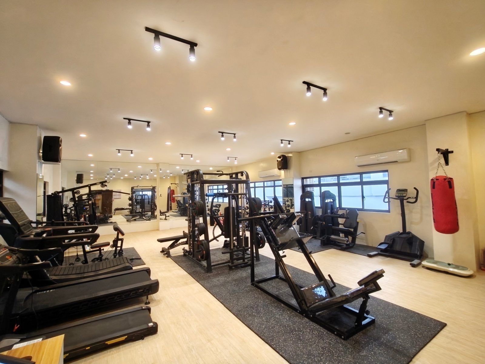 The main training floor at H Fitness Center, with racks, cardio machines and a punching bag